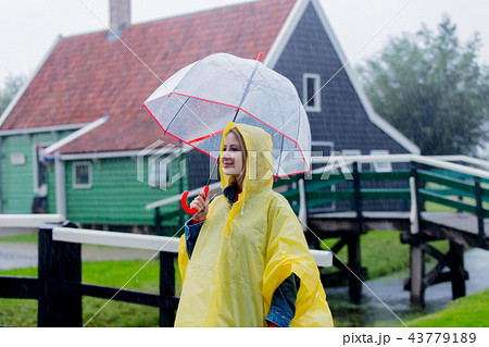 girl in rain suit with umbrella stay on bridge with dutch house 43779189