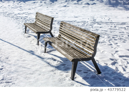 Two empty benches on snow covered ground Two empty benches on snow covered ground 43779522