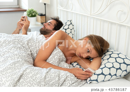Young couple with smartphones in their bed 43786187
