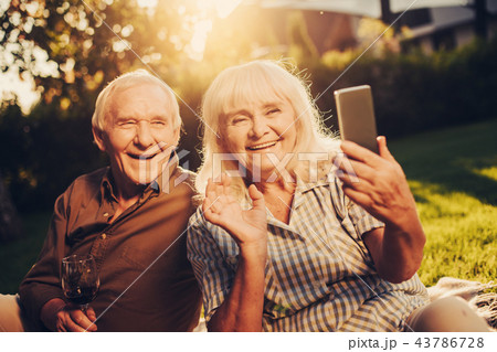 Happy smiling elderly couple using smartphone outdoors 43786728