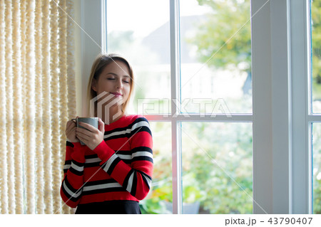 Young girl with cup of coffee stay near window Young girl with cup of coffee stay near window 43790407
