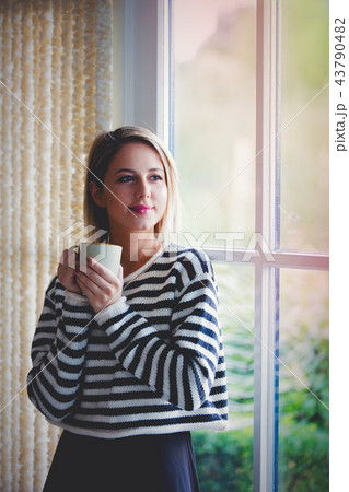 Young girl with cup of coffee stay near window Young girl with cup of coffee stay near window 43790482