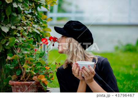 Girl with cup of coffee in garden Girl with cup of coffee in garden 43796467