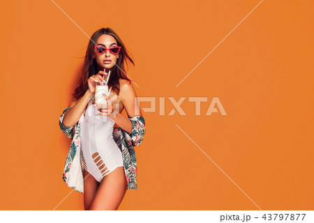 Woman in swimsuit holding beverage Woman in swimsuit holding beverage 43797877