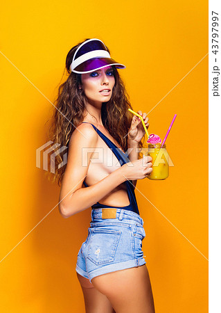 Sexy Woman in white swimsuit and blue jeans shorts, trendy visor holding beverage Sexy Woman in white swimsuit and blue jeans shorts, trendy visor holding beverage 43797997