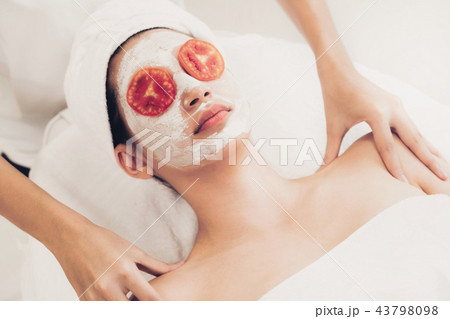 Woman get facial mask with tomato cream extract. Woman get facial mask with tomato cream extract. 43798098