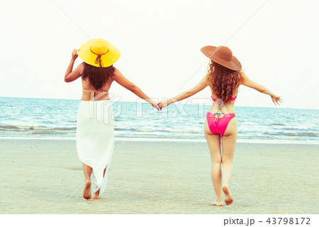Happy women go sunbathing at sand beach in summer. 43798172