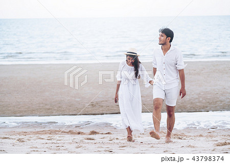 Happy young couple walk on the beach on honeymoon. 43798374