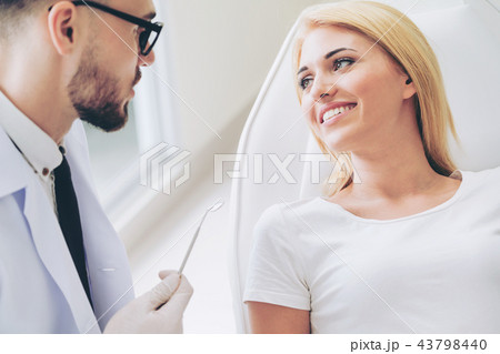 Young dentist talks with patient in dental clinic. 43798440