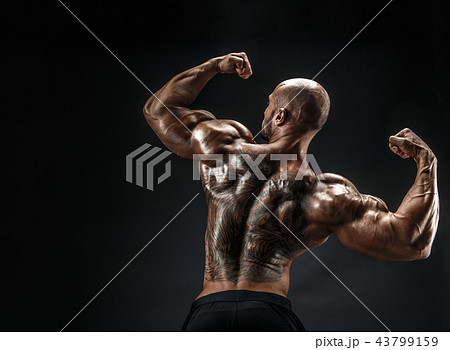 Unrecognizable muscular man with tattoo on back against of black background. Isolated. Unrecognizable muscular man with tattoo on back against of black background. Isolated. 43799159