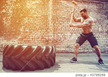 Sport Fitness Man Hitting Wheel Tire With Hammer Sledge Crossfit Training. Sport Fitness Man Hitting Wheel Tire With Hammer Sledge Crossfit Training. 43799299