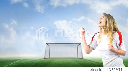 Soccer fan celebrating with fist and goal on pitch 43799554