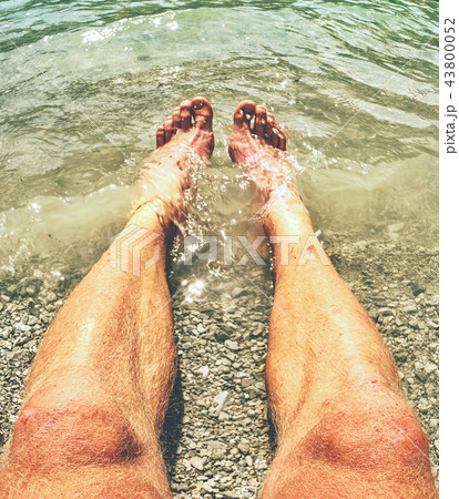 Hairy strong male legs are cooling in cold water  43800052
