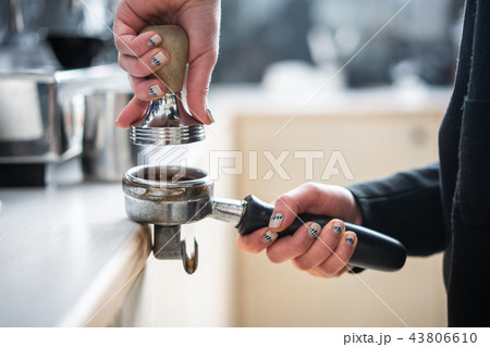 Barista presses ground coffee using tamper. Barista presses ground coffee using tamper. 43806610