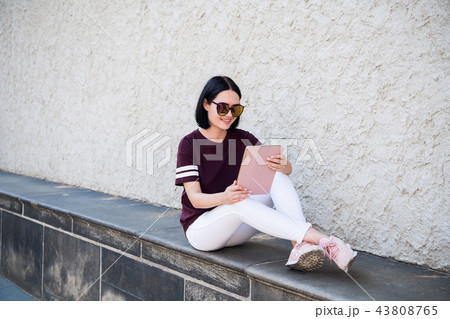 Happy woman in glasses using tablet pc in the street 43808765