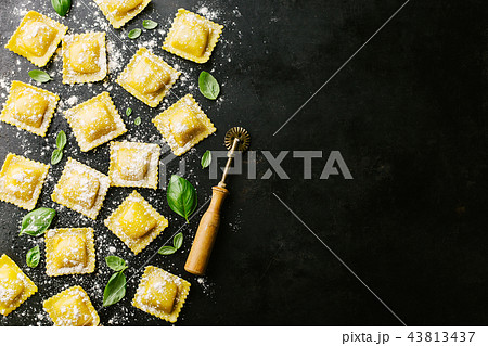 Raw ravioli with basil and flour on dark 43813437