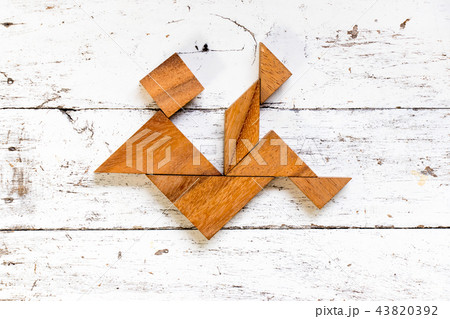 Tangram puzzle in falling man shape on white wood Tangram puzzle in falling man shape on white wood 43820392