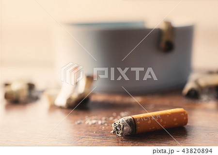 ashtray with cigarette on wood table. 43820894