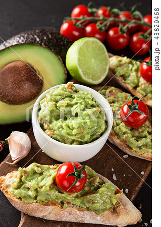 A delicious bowl of Guacamole with fresh ingredients on stone table. 43829468