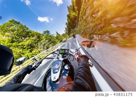 Motorcycle driver riding in Alpine highway, handlebars view, Austria, Europe. 43831175