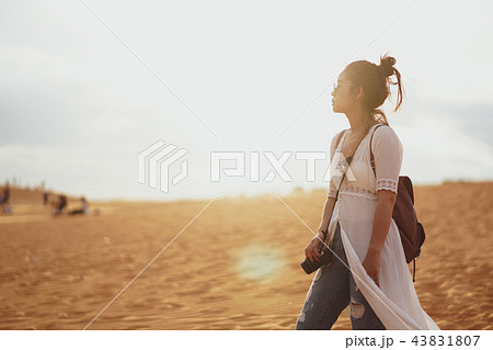 Woman exploring the desert, sandy beach with bag. 43831807