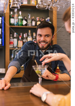 Handsome barman smiling and flirting with young visitor Handsome barman smiling and flirting with young visitor 43834214