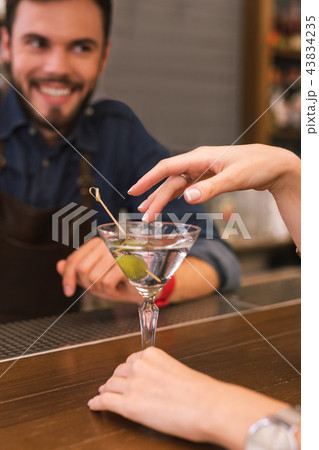 Young barman smiling and the client touching the glass Young barman smiling and the client touching the glass 43834235