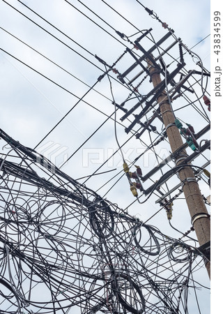 Telephone pole and chaotic mess of wires against sky 43834599