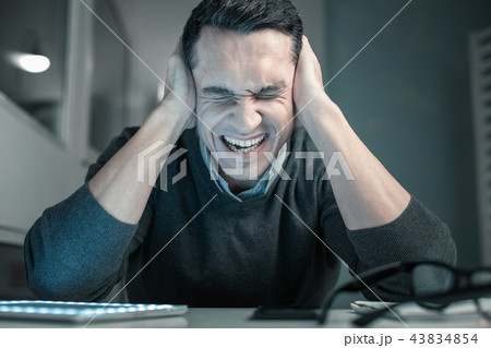 Upset young man squeezing head with hands Upset young man squeezing head with hands 43834854