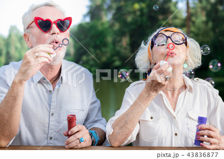 Funny pensioners wearing sunglasses and blowing soap bubbles Funny pensioners wearing sunglasses and blowing soap bubbles 43836877