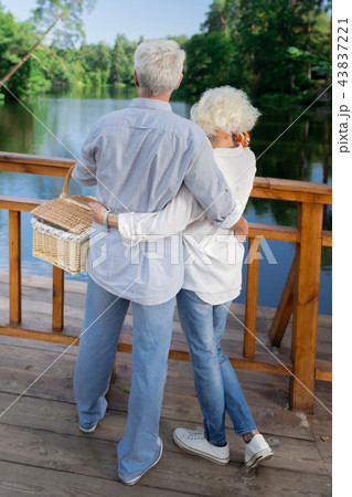Elderly couple holding picnic basket and looking at the river Elderly couple holding picnic basket and looking at the river 43837221