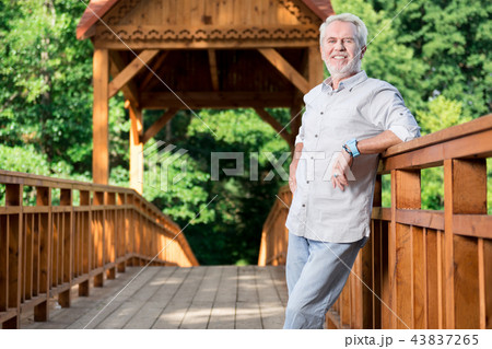 Happy aged man feeling good and smiling while standing on the bridge 43837265