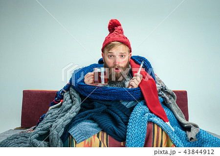 Bearded Man with Flue Sitting on Sofa at Home. Healthcare Concepts. Bearded Man with Flue Sitting on Sofa at Home. Healthcare Concepts. 43844912