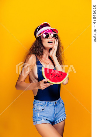 Woman in cap and swimwear hold slice of watermelon 43846010