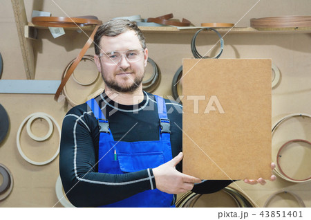 The manufacturer of furniture in special clothes and goggles keeps an empty plate for the text while 43851401