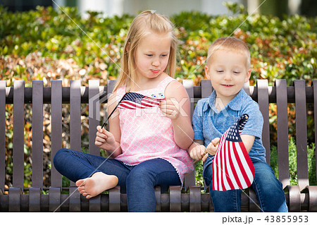 Sister and Brother Waving American Flags On Bench 43855953
