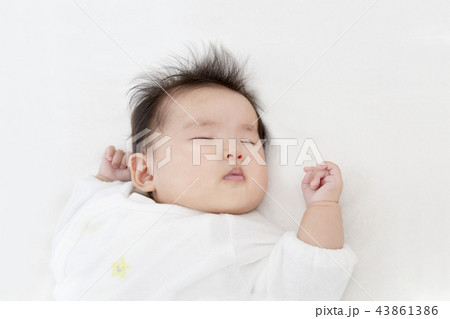 白いオーバーオールを着て眠る生後3ヶ月になった新生児。新生児、赤ちゃん、育児、健康のイメージ 43861386