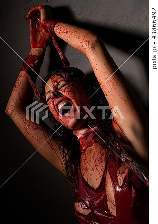 Screaming girl splashed with blood on the floor 43866492