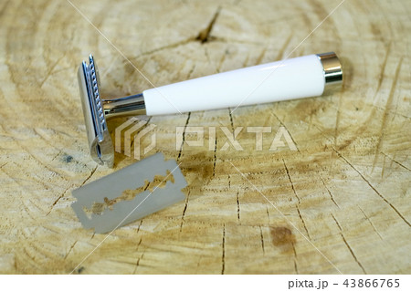 A traditional steel razor with a white bone handle and a steel razor blade on a natural wood A traditional steel razor with a white bone handle and a steel razor blade on a natural wood 43866765