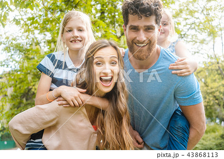 Family of four having fun  carrying the kids piggyback 43868113