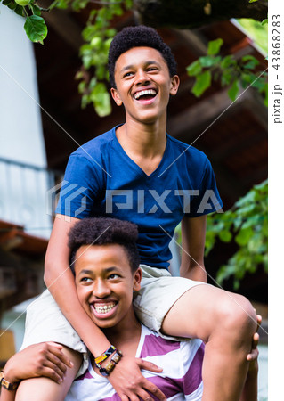Boy carrying his friend on shoulder Boy carrying his friend on shoulder 43868283