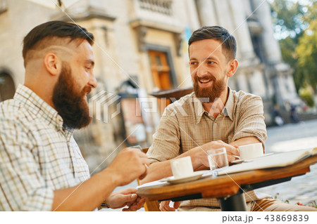 two men drink coffee at a cafe 43869839