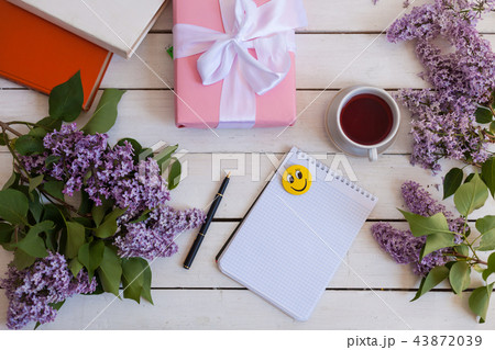 on the white table lilac, gift, notebook, cup of tea on the white table lilac, gift, notebook, cup of tea 43872039