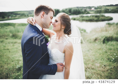 Romantic, fairytale, happy newlywed couple hugging and kissing in a park, trees in background 43874129