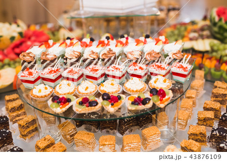 Delicious and tasty dessert table with cupcakes shots at reception closeup Delicious and tasty dessert table with cupcakes shots at reception closeup 43876109