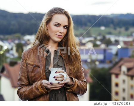 Beautiful young woman drinking coffee outdoors 43876203