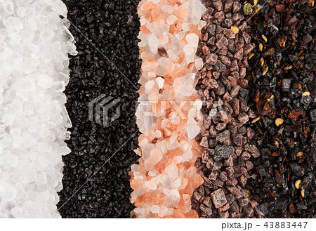 Various coarse grain salts on black stone background. Various coarse grain salts on black stone background. 43883447