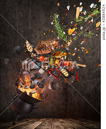 Kettle grill with hot briquettes, cast iron grate and tasty beef steaks flying in the air. Kettle grill with hot briquettes, cast iron grate and tasty beef steaks flying in the air. 43884024