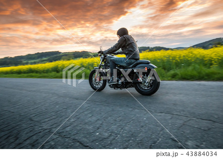 Man riding sportster motorcycle during sunset. Man riding sportster motorcycle during sunset. 43884034