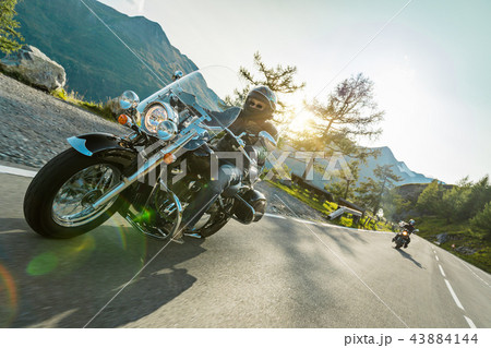 Motorcycle driver riding japanese high power cruiser in Alpine highway on famous Hochalpenstrasse, Austria. 43884144